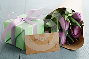 Tulip flowers with green gift box and paper card on blue wood table for valentines day
