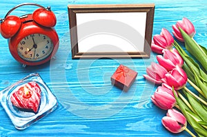 Tulip flowers and empty photo frame on wooden background with copy space. Woman day concept. Romantic background.