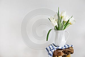 Tulips bouquet in white vase on wooden rustic chair photo