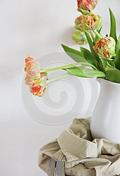 Tulips bouquet in white vase on wooden rustic chair photo