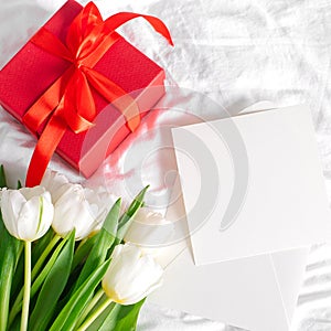 Tulips flowers, red gift box and empty card for text. Mock-up. Concept of womans day, mothers day