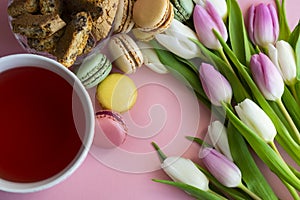 Tulips, tea and sweets on pink background