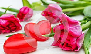 Tulips with two red hearts on white wooden background