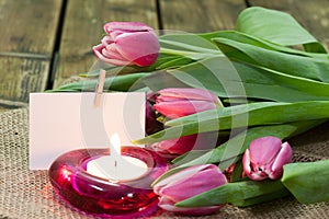 Tulips in vase and burning candle