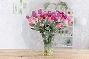 Tulips in a vase on a wooden table. Scandinavian interior