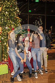 Group of teenagers pose with Santa in front of Christmas tree at Williams Lodge at Gathering Place public