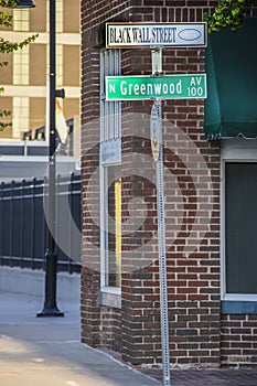 Tulsa USA Street Sign that reads Black Wall Street and Greenwood Av against brick building-Site of historic Tulsa Race photo