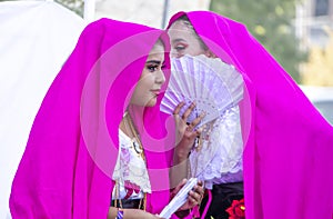 Tulsa USA - Two beautiful young girls gossip behind a hand fan as they prepare to dance in costume at a Latin