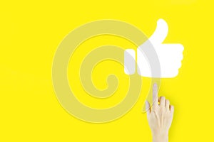 Tumb up concept. Young woman`s hand finger pointing with hologram hand tumb up on yellow background. Congratulate, good and like