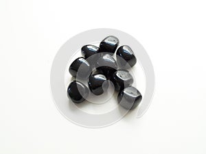 Tumbled Black Obsidian stones close up on table for crystal therapy treatments and reiki