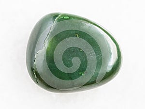 tumbled green nephrite gemstone on white marble