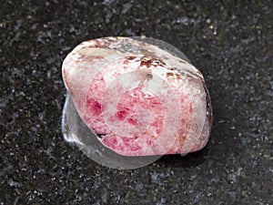 tumbled pink rhodonite gem stone on dark