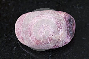 tumbled rhodonite gem on dark background