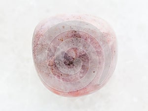 tumbled rhodonite gem stone on white marble