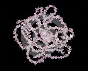 Tumbled rose quartz stone surrounded by rose quartz strings