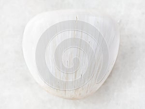 tumbled Scolecite gemstone on white marble photo