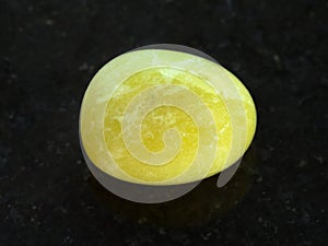 tumbled yellow calcite gemstone on dark