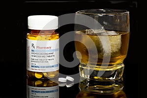 Tumbler of liquor and hydrocodone/APAP prescription.  Mixing Drugs and alcohol concept photo