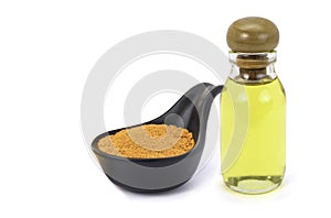 Tumeric powder in ceramic spoon and glass bottle of extracted essential turmeric oil isolated on white