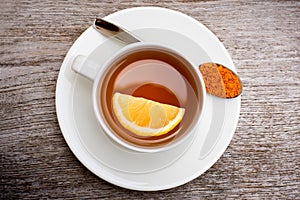 Tumeric tea with lemon slice on wood background.