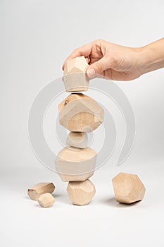 Tumi-ishi puzzle game. A woman or a girl places her hand on another block of wood on top of an unstable tower. The process of the