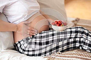 Tummy of a pregnant woman and strawberries photo