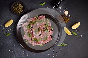 tuna carpaccio - slices of fresh raw tuna fillet on black ceramic plate