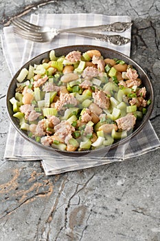 Tuna celery butter beans salad with green onions and capers close-up in a plate. Vertical