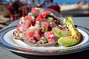 Tuna ceviche tostada served on a plate with avocado and lime