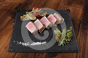 Tuna fillet slices with salad on gray slate