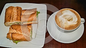 Tuna melt in baguette served with hot coffee  cappuccino on wood table