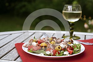 tuna salad with tomatoes, olives and rukkola, recipe in a Mediterranean style served in the garden on a wooden table, copy