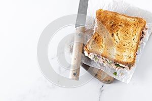 Tuna sandwich with mayo and vegetables on white marble background