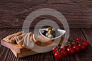 Tuna slices with tomatoes and olives on cutting board on wooden background closeup