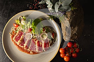 Tuna slices with vegetable salad of cherry tomatoes, radishes, onions, lettuce and adjika tomato sauce. Main fish dish