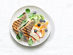 Tuna, spinach, mozzarella hot toast and fresh fruit - delicious healthy breakfast, brunch, snack on a light background.