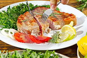 Tuna steak cooked on the electric grill. tunafish served on a plate with fresh herbs and vegetables. healthy nutritious