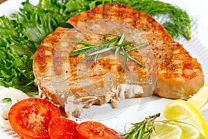 Tuna steak cooked on the electric grill. tunafish served on a plate with fresh herbs and vegetables. healthy nutritious