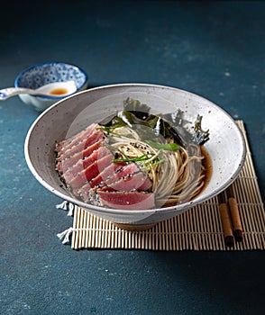 Tuna steak ramen. Japanese soup with noodles ramen, miso, fried tuna steak and seaweed algae. Top view. blue background