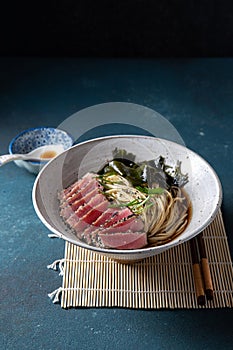 Tuna steak ramen. Japanese soup with noodles ramen, miso, fried tuna steak and seaweed algae. Top view. blue background.