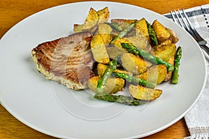 tuna steak served with potato wedges and asparagus photo