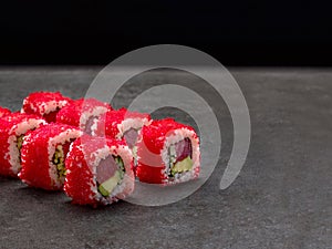 Tuna sushi roll with Red flying fish roe Tobiko on top. Served on Concrete background