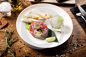 Tuna tartare: Guacamole quail egg baguette on a plate. Delicious healthy raw food closeup served for lunch on a table in