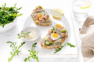 Tuna toast. Open sandwiches with whole grain bread, canned tuna, boiled egg, avocado and arugula