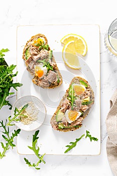 Tuna toast. Open sandwiches with whole grain bread, canned tuna, boiled egg, avocado and arugula