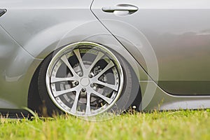 Tuned alloy wheels with a wide rim on an lowered silver car standing on the grass