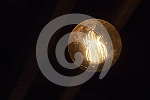 Tungsten light bulb in round shape on black background