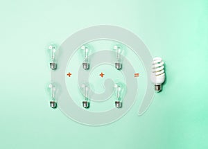 Tungsten light bulbs and energy-saving bulb on green background