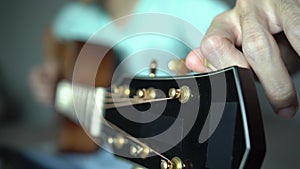 Tuning acoustic guitar string by adjusting tuning machines