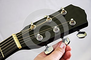 Tuning an acoustic guitar. White background. Close-up.